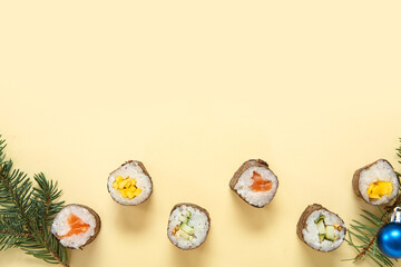 Christmas composition with tasty sushi rolls and fir tree branches on beige background