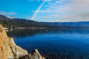 a gorgeous winter landscape at Lake Tahoe with blue lake water, lush green trees and plants and...