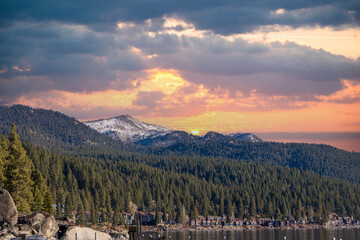 a gorgeous winter landscape at Lake Tahoe with blue lake water, lush green trees and plants and...