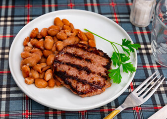 Appetizing roasted beef burger patty served with beans on platter