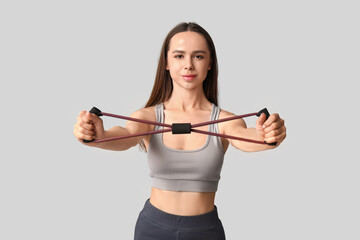Young female trainer with fitness expander on white background