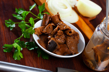 White salad bowl with canned red pine mushrooms, white onions and fresh green parsley on wooden table