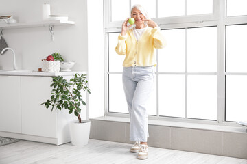 Mature woman pointing at apple in kitchen