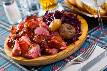 Close up of delicious baked pork knuckle with stewed red cabbage and baked onion