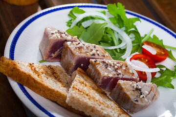 Tuna fillet Tataki served with pieces of toasted bread and herbs
