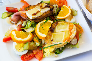 French cuisine. Salad with goat cheese, oranges, vegetables and honey