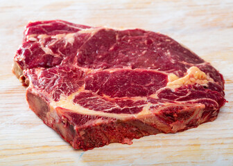 Fresh chop of beef on natural wooden background, top view