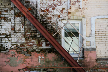 Geometric pattern of a straight iron staircase on the background of a brick wall with several...