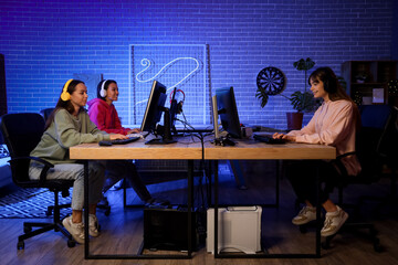 Group of young women playing computer games in club at night