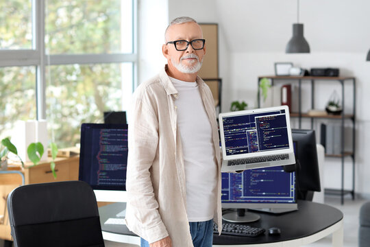 Mature programmer with laptop in office