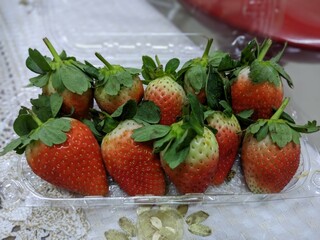 A plastic container filled with fresh, red strawberries.