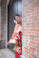 A Japanese woman in her 20s, wearing a red kimono (hakama), a staple of Japanese university...
