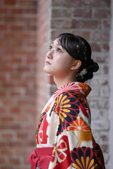 A Japanese woman in her 20s, wearing a red kimono (hakama), a staple of Japanese university...