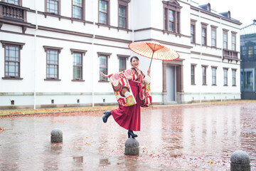 A Japanese woman in her 20s, wearing a red kimono (hakama), a staple of Japanese university...