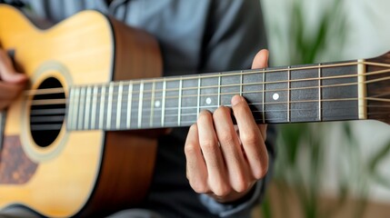 Fototapeta premium Close-up of a person's hands playing an acoustic guitar, The focus is on the fingers fretting the strings