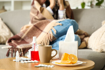 Medicines with lemon on table against ill woman at home, closeup