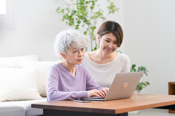 若い女性にパソコン操作を習うシニア女性