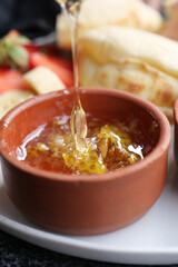 Golden Honey Drizzling Luxuriously in a Rustic Clay Dish with Fresh Fruits