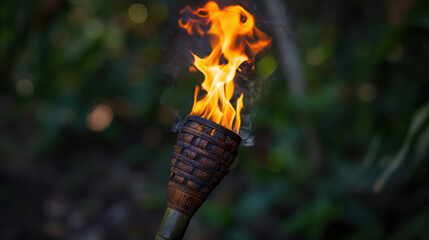 Lit tiki torch in lush garden setting with blurred green background