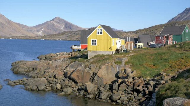 Colorful traditional Nordic houses by the seaside on a calm and sunny day. Filmed in Kulusuk, a small arctic village (settlement) in southeastern Greenland.