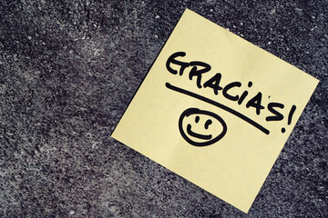 Thank you in spanish written on a post-it or note.