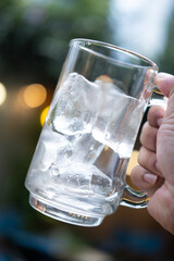 Ice in a glass mug on man hand with bokeh background