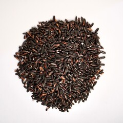 Pile of uncooked raw black or purple rice isolated on square white background from top angle view.