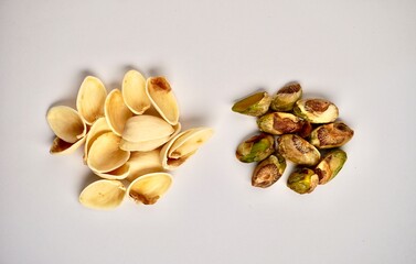 Pile of separated pistachio nuts and shell food objects isolated on horizontal white background.