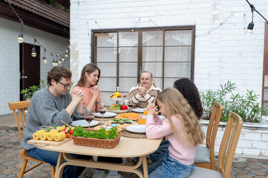 Multiracial lovely family saying a prayer before having dinner party. 