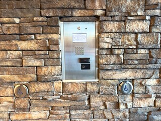 metal intercom panel mounted on a stone wall