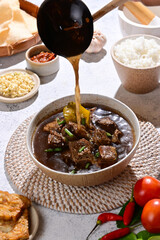 Rawon is a traditional Indonesian beef soup with a rich, black broth made from keluak nuts, aromatic spices, and herbs, typically served with rice and toppings like sprouts or sambal.