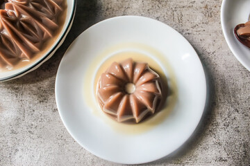 Severals plates of chocolate jelly pudding, arranged closely together as dessert.