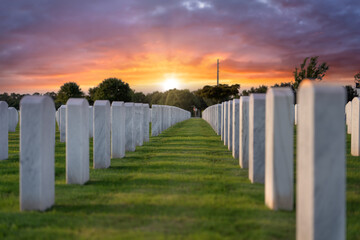 American army Sarasota National Cemetery with rows of white tombstones on green grass at sunset....
