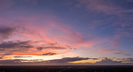 Evening sunset sky with colorful clouds over dark land. Panoramic skyscape