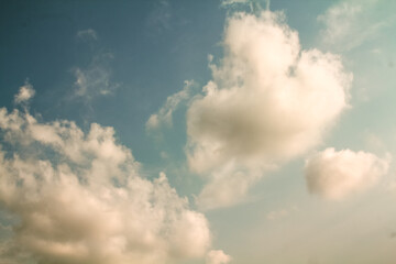 A summer daytime sky filled with thick cumulus clouds.