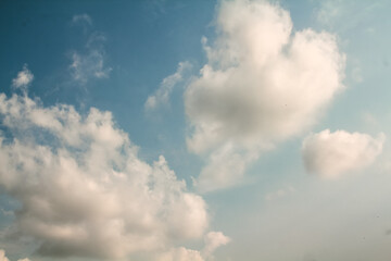 A summer daytime sky filled with thick cumulus clouds.