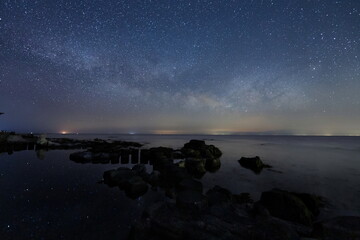海岸の水面に輝く星々と能登半島の星空