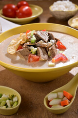 Soto Betawi is a creamy, coconut milk-based soup from Jakarta Indonesia, featuring beef or offal, potatoes, and spices, served with rice, lime, and sambal - selective focus