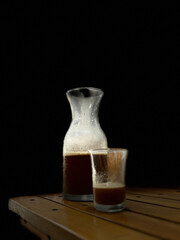 Glass Cup of Coffee on Wooden Table in Dark Minimalist Setting. A simple composition of a glass...