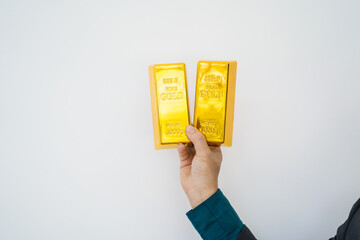 Close-up of a businessman holding shiny gold bars, symbolizing wealth and investment, isolated on a...