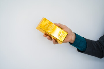 Close-up of a businessman holding shiny gold bars, symbolizing wealth and investment, isolated on a...