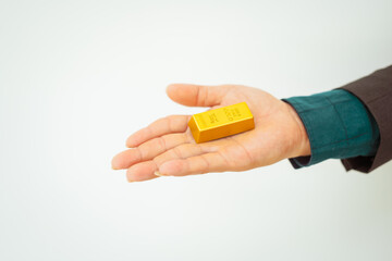Close-up of a businessman holding shiny gold bars, symbolizing wealth and investment, isolated on a...