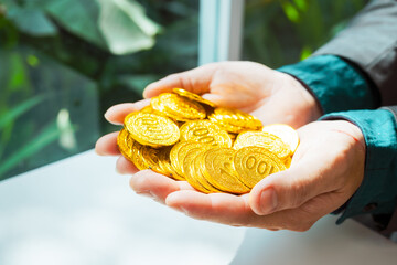 Close-up of a businessman holding shiny gold bars, symbolizing wealth and investment, isolated on a...