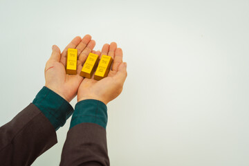 Close-up of a businessman holding shiny gold bars, symbolizing wealth and investment, isolated on a...
