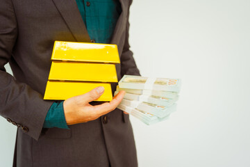 Close-up of a businessman holding shiny gold bars, symbolizing wealth and investment, isolated on a...