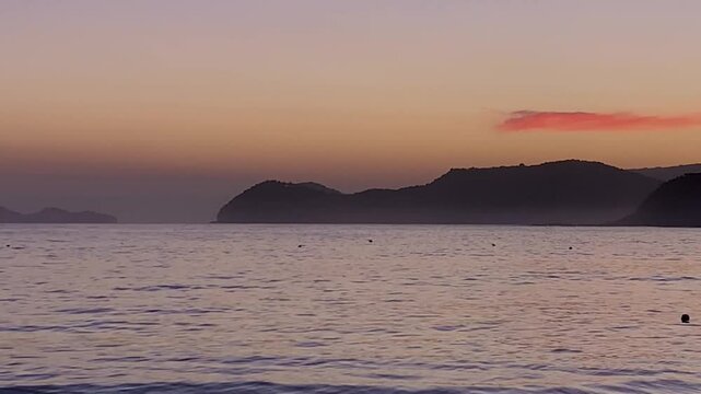 Final de tarde no crep&uacute;sculo com o mar bem calmo e o c&eacute;u em tom de rosa. Ao fundo, &agrave; esquerda, uma ilha bem conhecida no Litoral Norte chamada de As Ilhas.