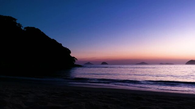 Hora do crep&uacute;sculo, noite chegando, o canto da praia j&aacute; est&aacute; escuro e o mar bem tranquilo. Ao fundo, quatro ilhas: Ilha Mont&atilde;o de Trigo, Ilha dos Gatos, Ilha das Couves e Ilha As Ilhas.