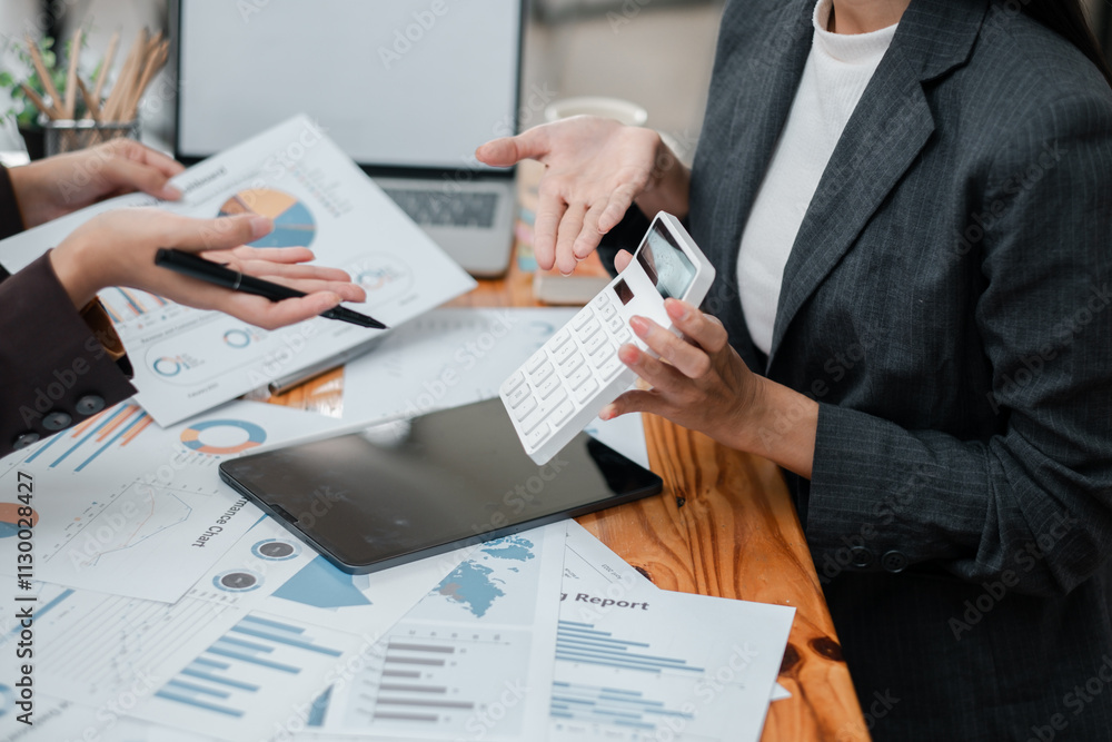 Aufkleber professionals discussing financial reports with charts and graphs, using a calculator and tablet in 