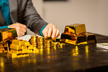 A businessman sits at his desk in a nighttime office, using a laptop to analyze gold bar prices,exchange rates, and investment plans in gold trading, mining,and the stock market amid price increases