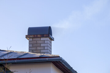 
White smoking brick chimney on blue sky background